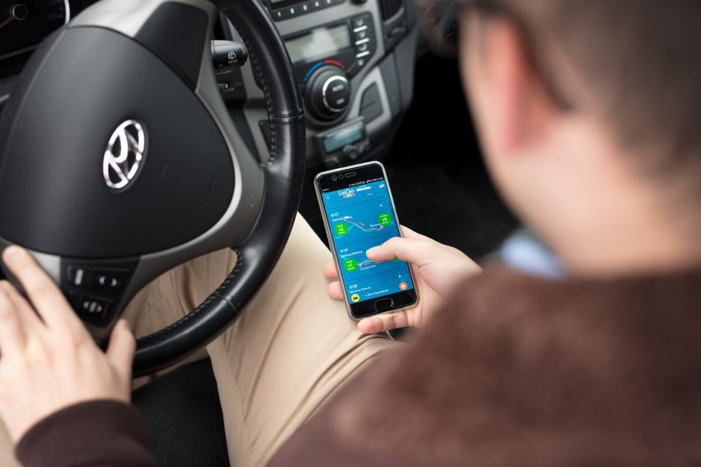 Mann nutzt Smartphone im Auto.