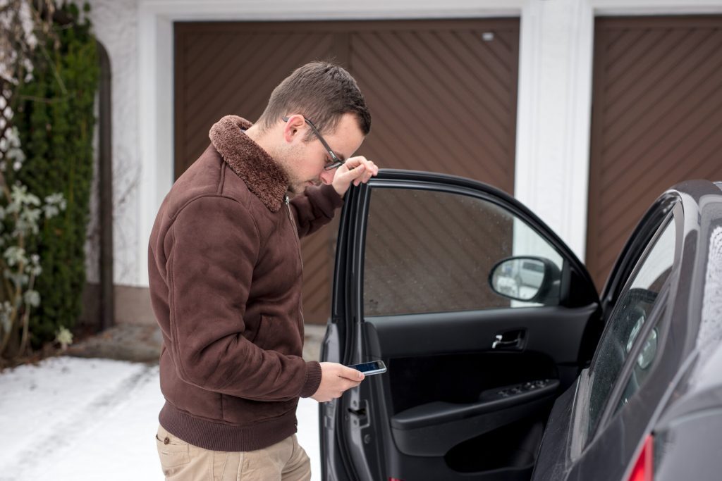 Mann steht neben einem Auto.